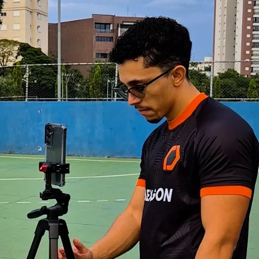 Fotógrafo posicionando celular em tripé na beira da quadra